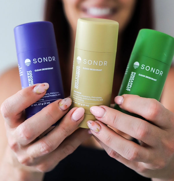 Woman holding three full size SONDR deodorants